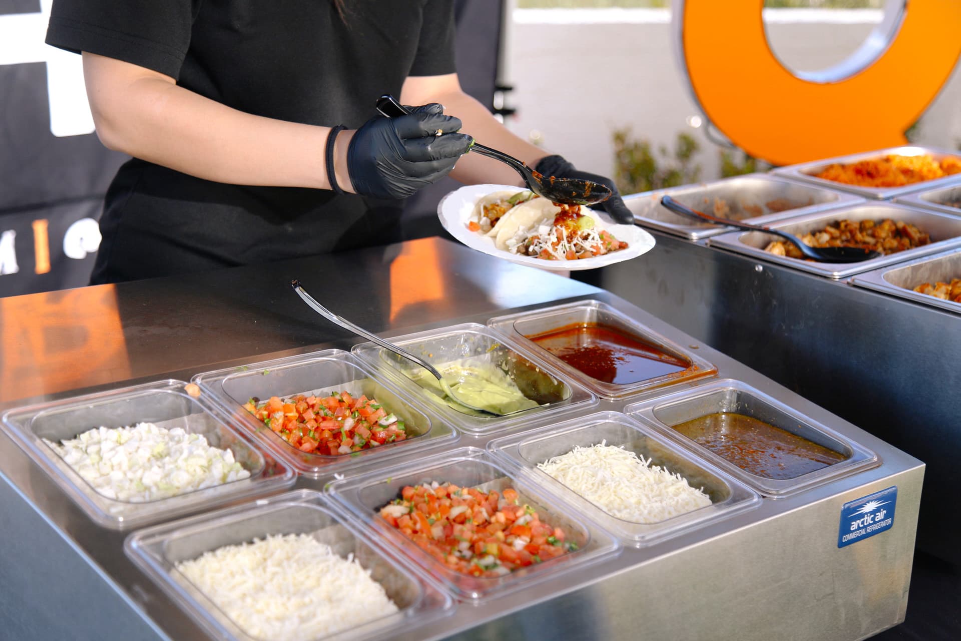 A Mesquite Fresh team member adds salsa to a plate of tacos